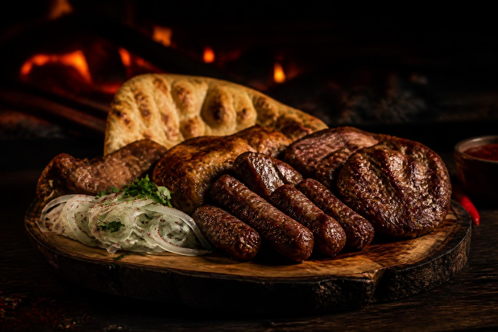 Balkan mixed grill met ćevapi, gegrild vlees en vers brood op een houten plank